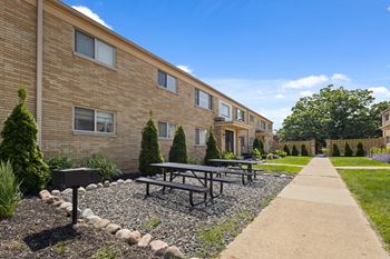 Outdoor picnic area with grills and tables at Monon Court Apartments in Broad Ripple, IN, offering affordable vintage one- and two-bedroom homes near the Monon Trail.